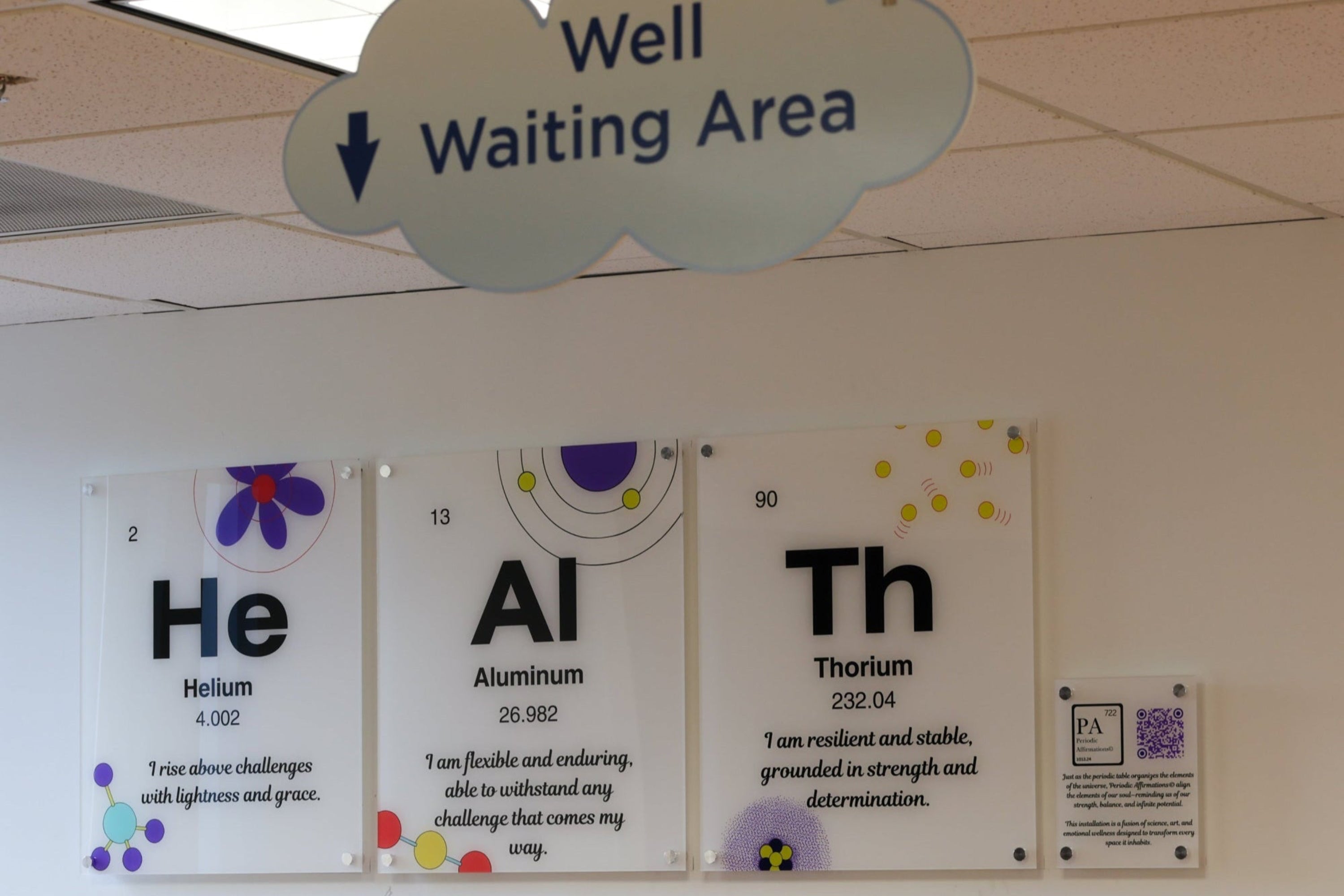 Sign indicating 'Well Waiting Area' above periodic table-themed wall art.